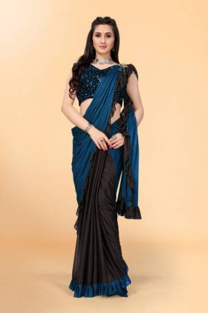Get glowing in this pretty ready-to-wear lycra saree. The colorblocked saree is made of lycra fabric in black and teal color with ruffles detailing on hem beautified by brooch on shoulder making it more attractive. This saree comes along with unstitched velvet diamond embellished fabric blouse piece. It is perfect for parties, family functions when paired with beautiful jewellery and pair of heels to complete the look.