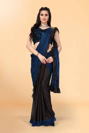 Get glowing in this pretty ready-to-wear lycra saree. The colorblocked saree is made of lycra fabric in black and navy blue color with ruffles detailing on hem beautified by brooch on shoulder making it more attractive. This saree comes along with unstitched velvet diamond embellished fabric blouse piece. It is perfect for parties, family functions when paired with beautiful jewellery and pair of heels to complete the look.