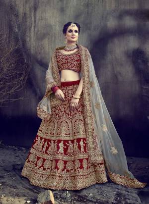 Adorn The Beautiful Rich And Royal Look Wearing This Lehenga Choli In Maroon Color Paired With Grey Colored Dupatta. Its Blouse And Lehenga Are Fabricated On Velvet Paired With Net Dupatta. It Has Heavy Embroidery All Over The Blouse, Lehenga And Dupatta. Grab This Heavy Bridal Lehenga Now.