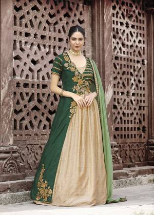 New And Unique Patterned Designer Floor Length Suit Is Here In Beige And Green Color Paired With Green Colored Bottom And Dupatta. Its Top Is Fabricated On Art Silk Paired With Santoon Bottom And Chiffon Dupatta. Buy This Designer Suit Now.