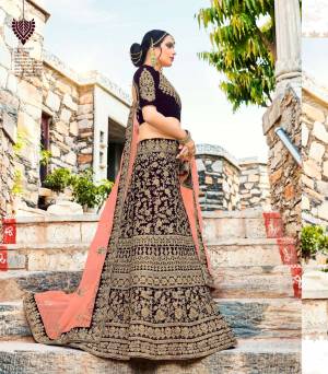 New And Unique Shade In Lehenga Choli IS Here With this Heavy Designer Lehenga Choli In Dark Wine Color Paired With Contrasting Peach Colored Blouse. This Lehenga And Choli Are Fabricated On Velvet Paired With Net Fabricated Dupatta. Buy This Now Before the Stock Ends.