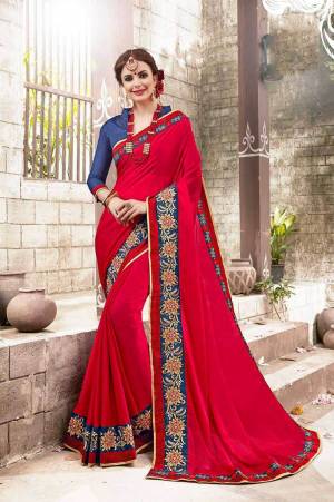 Adorn The Pretty Angelic Look Wearing This Saree In Red Color Paired With Contrasting Blue Colored Blouse. This Saree Is Fabricated On Chiffon Paired With Art Silk Fabricated Blouse. It Is Beautified With Embroidered Lace Border.