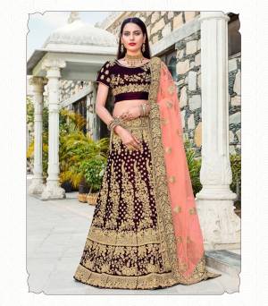Color That Gives Your Personality A Royal Queen Look, Adorn The Beautiful Queen Look Wearing This Designer Lehenga Choli In Dark Maroon Color Paired With Contrasting Peach Colored Dupatta. Its Blouse And Lehenga Are Fabricated On Velvet Paired With Net Fabricated Dupatta. Buy This Heavy Lehenga Choli Now.