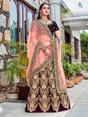Color That Gives Your Personality A Royal Queen Look, Adorn The Beautiful Queen Look Wearing This Designer Lehenga Choli In Dark Wine Color Paired With Contrasting Peach Colored Dupatta. Its Blouse And Lehenga Are Fabricated On Velvet Paired With Net Fabricated Dupatta. Buy This Heavy Lehenga Choli Now.