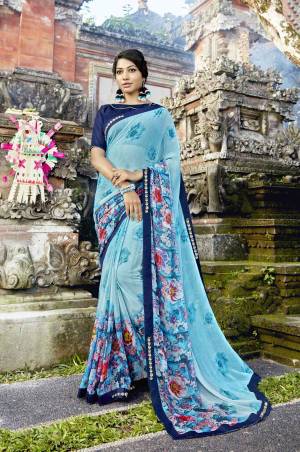 Add This Pretty Saree To Your Wardrobe In Light Blue Color Paired With Navy Blue Colored Blouse. This Saree Is Fabricated On Georgette Paired With Art Silk Fabricated Blouse. It Is Beautified With Floral Prints Over Its Border. 
