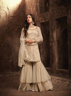 Grab This Beautiful Designer Sharara Suit In Off-White Color Paired With Off-White Colored Bottom And Dupatta. Its Top Is Fabricated On Net Paired With Nat And Santoon Bottom And Net Dupatta. It Has Love;y Embroidery All Over It. Buy This Designer Suit Now.