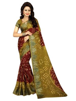 A Must Have Unique Shade In Every Womens Wardrobe Is Here With This Pretty Saree In Maroon And Olive Green Color Paired With Olive Green Colored Blouse. This Saree And Blouse are Fabricated On Art Silk Beautified With Bandhani Prints All Over.