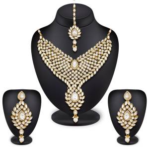 Beautifully Carved Designer Necklace Set Is Here In Golden Color Beautified With White Colored Stones. Its Lovely Pattern And Pretty Maang Tika Will Earn You Lots Of Compliments From Onlookers.