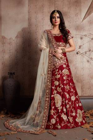 Maroon velvet lehenga with zari embroidery highlighted with topaz crystals paired with a champagne cream dupatta, with a machine embroidered border.