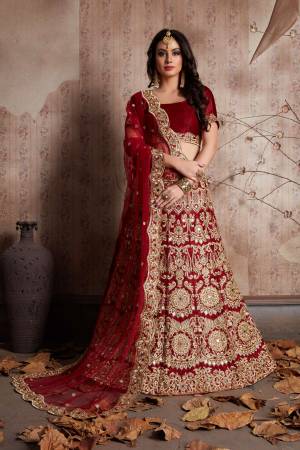 Maroon velvet lengha choli with zari embroidery and mirror work all over. It is paired with a maroon net cutwork dupatta with mirror work.