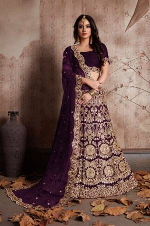 Wine color velvet lengha choli with zari embroidery and mirror work all over. It is paired with a wine color net cutwork dupatta with mirror work.