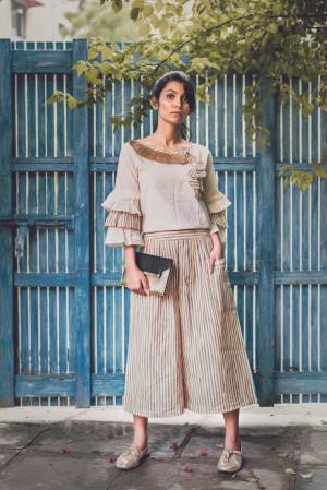 Beige linning khadi calf length pant with two big outer pocket packed with jute lace Paired With  off white pagoda sleeves top embellished jute lace at the neck line and hangging teassel