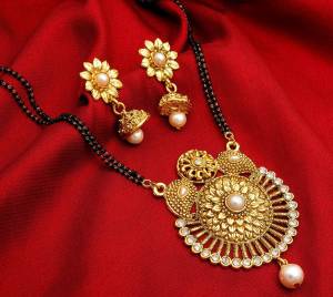 For A Traditional Look, Grab This Lovely Mangalsutra Set In Golden Color Beautified With Pearl And Diamond Work. This Set Also Comes With A Lovely Pair Of Earrings. Buy Now.