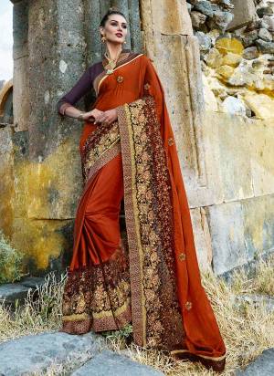 New And Unique Shade In Orange Is Here With This Saree In Rust Orange Color Paired With Contrasting Wine Colored Blouse. This Is Fabricated On Silk Georgette Paired With Art Silk Fabricated Blouse. It Has Heavy Embroidery Over Its Broad Lace Border.