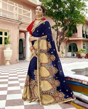Grab This Heavy Designer Saree In Dark Blue Color Paired With Contrasting Red Colored Blouse. This Saree Is Fabricated On Georgette Paired With Art Silk Fabricated Blouse. It Is Beautified with Heavy Embroidery Over Its Broad Border. 