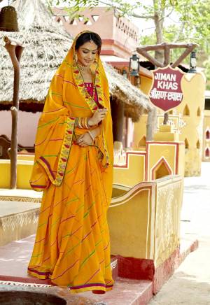 Celebrate This Festive Season Wearing This Bandhani Printed Saree In Musturd Yellow Color Paired With Dark Pink Colored Blouse. This Saree Is Georgette Based Paired With Art Silk  Blouse. It Also Has Attractive Embroidered Lace Border.