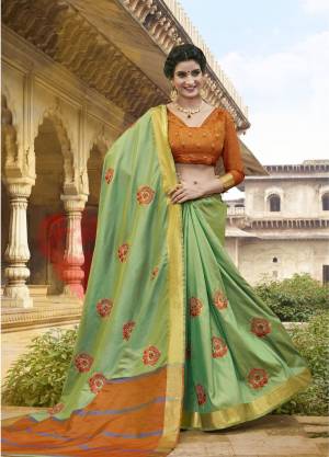 Celebrate This Festive Season Wearing this Pretty Light Green Colored Saree Paired With Contrasting Orange Colored Blouse. This Saree Is Fabricated On Satin Silk Paired With Art Silk Fabricated Blouse. It Is Beautified With Resham Embroidery And Moti Work. 