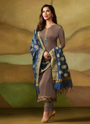 New Shade Is Here To Add Into Your Wardrobe With This Designer Straight Suit In Sand Grey Color Paired With Sand Grey Bottom And Contrasting Blue Colored Dupatta. Its Top Is Fabricated On Satin Georgette Paired With Santoon Bottom And Banarasi Silk Dupatta. 