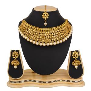 Grab This Elegant Choker Patterned Neckalce Set In Golden Color Paired With A Maang Tika And Earrings Set. This Necklace Can be Paired With Suit, Lehenga Or Saree. Buy Now.
