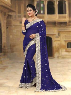 For A Festive Look, Grab This Beautiful Saree In Navy Blue Color Paired With Navy Blue Colored Blouse. This Saree And Blouse Are Georgette Based Beautified with Jari Embroidery And Moti Work Which IS Making This Saree Heavy. 
