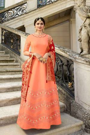 A Must Have Shade In Every Womens Wardrobe Is Here With This Designer Floor Length Gown In Dark Peach Color Paired With Contrasting Red Colored Dupatta. Its Top Is Silk based Paired With Banarasi Silk Dupatta. Buy Now.