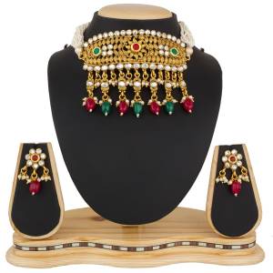 Give And Enhanced Look To Your Neck With This Heavy Choker Necklace Set In Golden Color Beautified With Maroon And Green Colored Stone Work.
