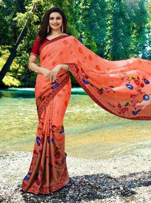 Bright And Visually Appealing Color Is Here With This Designer Saree In Orange Color Paired With Contrasting Maroon Colored Blouse. This Saree Is Georgette Based Beautified With Prints Paired With Art Silk Fabricated Blouse. 