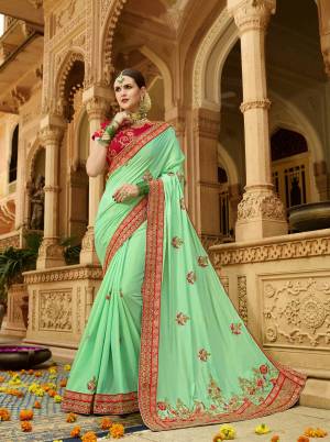 For A Proper Traditional Look, Grab This Beautiful Designer Saree In Light Green Color Paired With Contrasting Red Colored Blouse. This Saree And Blouse Are Silk Based Beautified With Heavy And Attractive Embroidery .
