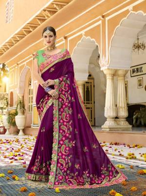 Bright And Visually Appeaking Color Is Here With This Designer Heavy Saree In Dark Purple Color Paired With Contrasting Green Colored Blouse. This Saree And Blouse Are Silk Based Beautified With Heavy Embroidery. 