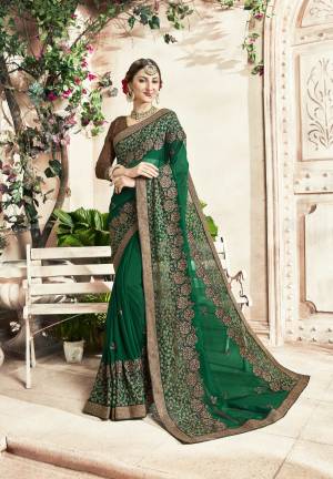 Celebrate This Festive Season Wearing This Designer Saree In Dark Green Color Paired With Brown Colored Blouse. This Saree IS Georgette Based Paired With Art Silk Fabricated Blouse. It Has Heavy Embroidery Over All The Border. 