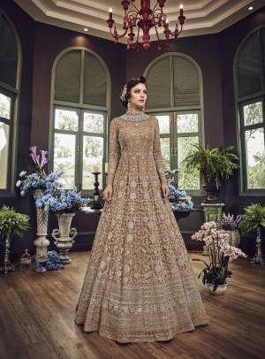 Add This Beautiful Heavy Designer Floor Length Suit In Beige Color Paired With Beige Colored Bottom And dupatta. Its Top And Dupatta Are Net Fabricated Paired With Art Silk Bottom. Also Its Top Is Beautified With Heavy Embroidery All Over.