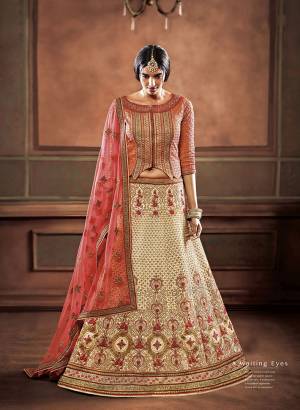 This Wedding Season, Be Most Stunning Wearing This Heavy Designer Lehenga Choli In Light Orange Colored Blouse Paired With Beige Colored Lehenga and Peach Colored Dupatta. It Is Silk Based Paired With Net Fabricated Dupatta. Buy Now.