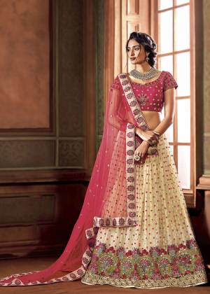 Add This Beautiful Heavy Designer Lehenga To Your Wardrobe In Dark Pink Colored Blouse Paired With Cream Colored Lehenga And Dupatta. It Is Silk Based Paired With Net Fabricated Dupatta. Its Pretty Combination Will Earn You Lots Of Compliments From Onlookers. 