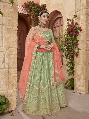 Subtle Shades Gives A Elegant And Pretty Look To Your Personality, So Grab This Heavy Designer Lehenga Choli In Light Green Color Paired With Contrasting Peach Colored Dupatta. It Is Fabricated On Satin Silk Paired With Net Fabricated Dupatta. Buy Now.