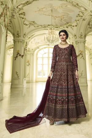 For A Royal Look, Grab This Heavy designer Floor Length Suit In Maroon Color Paired With Maroon Colored Bottom And dupatta. Its Top And Dupatta Are Net Based Paired With Santoon Bottom. Buy Now.