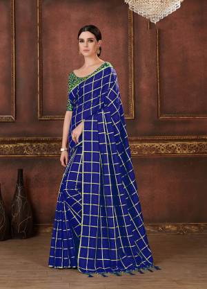 Here Is A Pretty Bright Shade With This Saree In Royal Blue Color Paired With Contrasting Dark Green Colored Blouse. This Saree And Blouse are Silk based Beautified With Prints, Embroidery And Tassels. It Is Light Weight And Having A Very Trendy Checks Pattern.
