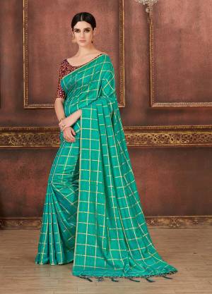 Here Is A Pretty Bright Shade With This Saree In Sea Green Color Paired With Contrasting Wine Colored Blouse. This Saree And Blouse are Silk based Beautified With Prints, Embroidery And Tassels. It Is Light Weight And Having A Very Trendy Checks Pattern.