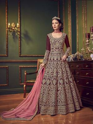 Here Is A Beautiful Designer Floor Length Suit In Maroon Color Paired With Contrasting Pink Colored Dupatta. Its Top And Bottom Are Silk Based With Full Embroidery Over The Top Paired With Net fabricated Dupatta. Buy This Now.