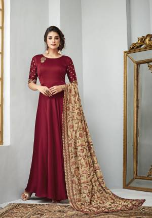 Here Is A Beautiful Designer Floor Length Suit With A Very Royal Color Pallete. Its Top And Bottom Are In Maroon Color Paired With Beige Colored Dupatta. Its Top Is Fabricated On Satin Georgette Paired With Santoon Bottom And Heavy Embroidered Art Silk Dupatta. Buy Now.