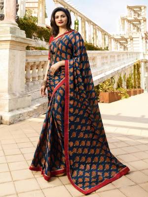 For Your Casual Or Semi-Casual Wear, Grab This Printed Saree In Navy Blue Color Paired With Contrasting Red Colored Blouse. This Saree Is Fabricated On Georgette Paired With Art Silk Fabricated Blouse. 