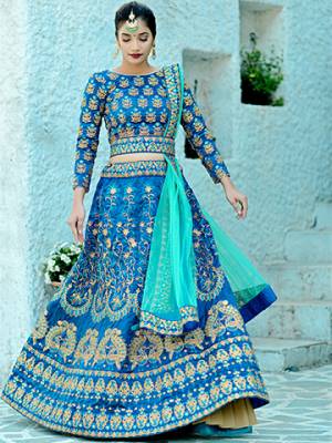 Another Beautiful Designer Heavy Lehenga Choli Is Here In Blue Color Paired With Contrasting Sea Green Colored Dupatta. Its Blouse And Lehenga Are Fabricated On Art Silk Paired With Net Fabricated Dupatta. Buy This Now.