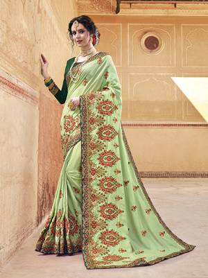 Here Is A Heavy Designer Saree In Light Green Color Paired With Dark Green Colored blouse. This Saree Ans Blouse Are Silk Based Beautified With Heavy Embroidery With Contrasting Thread Work Making It More Attractive. 