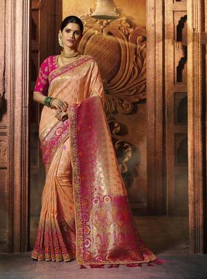 A Must Have Shade In Every Womens Wardrobe Is Here With This Beautiful Saree In Peach Color Paired With Contrasting Dark Pink Colored Blouse. Its Pretty Color Pallete And Rich Silk Fabric Will Earn You Lots Of Compliments From Onlookers. 