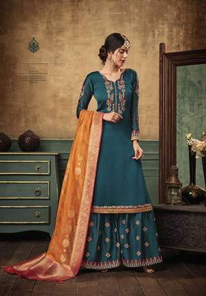 Add This Very Pretty Designer Sharara Suit With Bold Color Pallete. Its Top And Bottom Are In Teal Blue Color Paired With Contrasting Orange Colored Dupatta. This Semi-Stitched Suit Is Fabricated On Satin Georgette Paired With Banarasi Silk Fabricated Dupatta. 