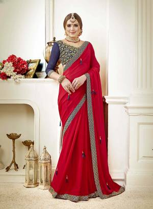 Adorn This Attractive looking Designer Saree In Red Color Paired With Contrasting Navy Blue Colored Blouse. This Saree Is Fabricated On Georgette Paired With Art Silk Fabricated Blouse. It Is Beutified With Embroidery Over Blouse And Tassels Over The Saree. 