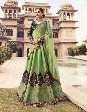 Here Is Another Heavy Designer Lehenga Choli In Shades Of Green Color Pallete. Its Blouse Is In Dark Green Color Paired With Light Green Colored Bottom And Dupatta. This Heavy Embroidered Lehenga Choli Is Silk Based Paired With Net Fabricated Dupatta And Another Banarasi Art Silk Dupatta. 