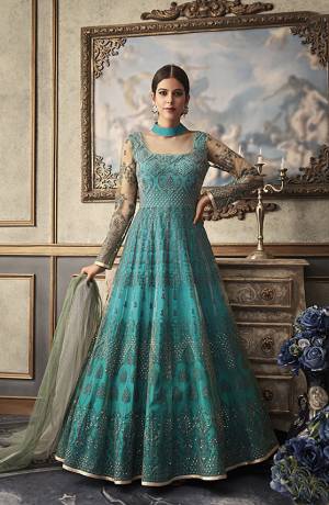 You Will Earn Lots Of Compliments Wearing This Heavy Designer Floor Length Suit In Turquoise Blue Color Paired With Contrasting Grey Colored Dupatta. Its Top And Dupatta Are Net Based Beautified With Heavy Embroidery Paired With Art Silk Fabricated Bottom And Inner. 