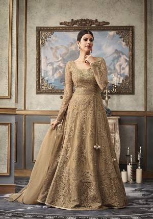 Flaunt Your Rich And Elegant Taste Wearing This Heavy Designer Floor Length Suit In Beige Color Paired With Beige Colored Bottom And Dupatta. Its Heavy Embroidered Top Is Net Based Paired With Art Silk Bottom and Net Fabricated Dupatta. Buy This Rich Designer Suit Now.