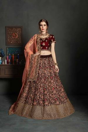 Get Ready For Your Big Day With This Latest Bridal Trend, Wearing This Heavy Designer Lehenga Choli In Maroon Color Paired With Contrasting Peach Colored Dupatta. This Heavy Embroidered Lehenga Choli Is Fabricated On Velvet Paired With Net Fabricated Dupatta. It Is Beautified With Heavy Embroidery and Stone Work. Buy Now