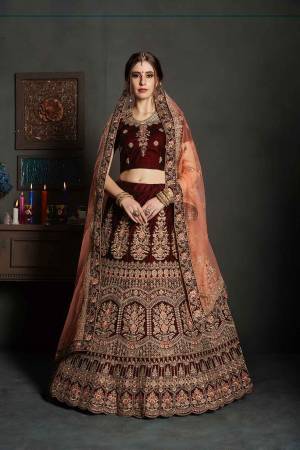 Here Is A Perfect Bridal Look For You In The Running Treand With This Heavy designer Lehenga Choli In Maroon Color Paired With Contrasting Peach Colored Dupatta. This Lehenga Choli Is Velvet Based Paired With Net Fabricated Dupatta.Its Fabric Also Ensures Superb Comfort Throughout The Gala